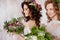 Two charming brides in beautiful spring wreaths on their heads. Beautiful young women in wedding dresses