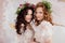 Two charming brides in beautiful spring wreaths on their heads. Beautiful young women in wedding dresses