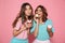 Two charming girls in colorful clothes enjoying tasty cupcakes,