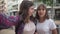 Two charming joyful teenage bloggers talking smiling standing on city street. Selfie camera POV of cheerful beautiful