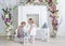Two charming little girls play in the light room decorated with flowers. Little girls and big candlestick