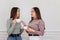 Two chatting young women friends in cafe drinking coffee. Girls chatting indoors