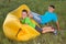 Two cheerful boys outdoors sitting on yellow airy sofa having fun and laughing, concept