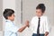 Two cheerful boys wearing shirts and ties shake each other hands as a token of friendship