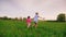 Two cheerful carefree kids hold hands. Together they run along the green meadow, having fun