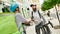 Two cheerful couriers, man and woman with backpacks talking outdoors while delivering food and products, using scooter