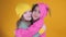 Two cheerful cute little girls hugging and having fun on a yellow background