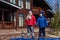 Two cheerful emotional children in jackets and hats stand near the big house and shout loudly holding hands in the spring on walk