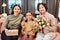 Two cheerful females and adorable little girl holding giftboxes and fresh tulips