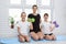 Two cheerful girls and their mother sit on the floor with dumbbells on the mat