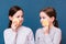 Two cheerful girls wash themselves with face sponges on a blue background. Child Hygiene Concept