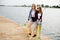 Two cheerful happy skater girls in hipster outfit having fun on a wooden pier during summer vacation
