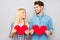 Two cheerful lovers holding red paper hearts