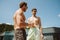 Two cheerful male friends drinking beer while standing on terrace in mountains