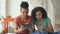 Two cheerful mixed race curly women shopping online with tablet computer and credit card at home