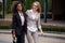 Two cheerful pretty african and caucasian businesswomen in stylish suits are walking along the park.