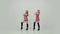 Two cheerleaders in uniform dancing synchronously on a white studio background in slow motion. Girls move their arms and