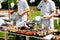 Two chefs prepare food outdoors for a party