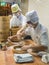 Two chefs in white uniforms preparing a dish of dough in a little kitchen, Singapore