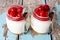 Two cherry cheesecakes in mason jars on a rustic wood