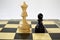 Two chess pieces of queen and pawn against each other on the background of the chessboard