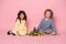 Two child girls friends in beautiful dress with rabbit, tulips, basket with colorful eggs on pink background