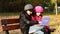 Two child girls sitting on bench and playing on laptop