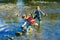 Two children with a backpack stands near a mountain river. Boy and girl looks at the creek. The kids walks through the