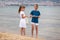 Two children boy and girl walking barefoot on sea shore water in summer