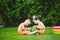 Two children, Caucasian brother and sister, sitting on green grass in backyard of house and hugging big tasty sweet watermelon