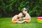 Two children, Caucasian brother and sister, sitting on green grass in backyard of house and hugging big tasty sweet watermelon