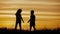 Two children dancing and enjoying nature on sunset. Child`s silhouette. Happy childs have fun, enjoying nature.