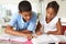 Two Children Doing Homework In Kitchen