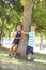 Two Children Hugging Tree In Park