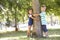 Two Children Hugging Tree In Park