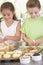 Two children in kitchen decorating cookies