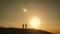 Two children launch a kite in the field at sunset.