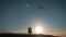 Two children launch a kite in the field at sunset.