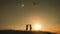 Two children launch a kite in the field at sunset.