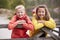 Two children leaning on a wooden fence in the countryside smiling to camera, close up