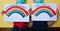 Two children with medical masks and rainbow messages in English and Spanish