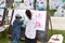 Two children painting on board outdoors in park. Activity in nature. Family and togetherness