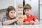 Two children playing board game Jenga building tower made of wooden blocks. Focused girl with tongue out pulling detail.