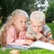 Two children read the book on a lawn
