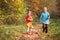 Two children run on wood autumn footpath