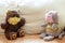 Two children`s soft toys bear and cat in color medical masks are sitting on light sofa with distance. Social distancing