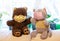 Two children`s soft toys bear and cat in color medical masks are sitting on light sofa on window background