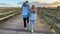 Two children sisters are walking in autumn day on a wooden road in swamps, Portugal. An active family lifetime