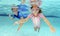 Two children swimming underwater in pool