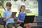 Two children teenager boy with laptop computer and young girl with digital tablet looking at screens outdoors sitting on